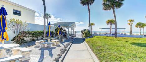 A pathway leading to a covered seating area with outdoor furniture and palm trees.
