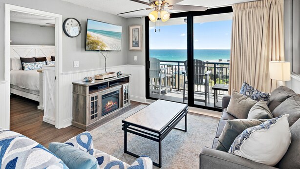 Un salon comprenant un canapé, une table basse, une cheminée et un balcon avec vue sur l’océan.