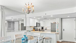 Une cuisine moderne avec des meubles blancs, un îlot central et un lustre.