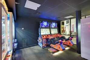 Un espacio de juegos con máquinas de arcade y un simulador de moto de nieve.