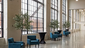 A spacious interior with large windows, modern furniture, and a high ceiling. - The Warehouse Hotel at Champion Mill (Hamilton)