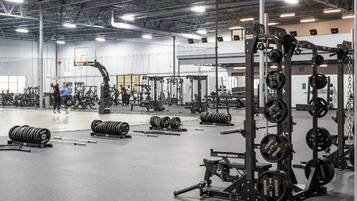 Un gimnasio con diverso equipamiento para levantamiento de pesas, incluyendo barras y discos.