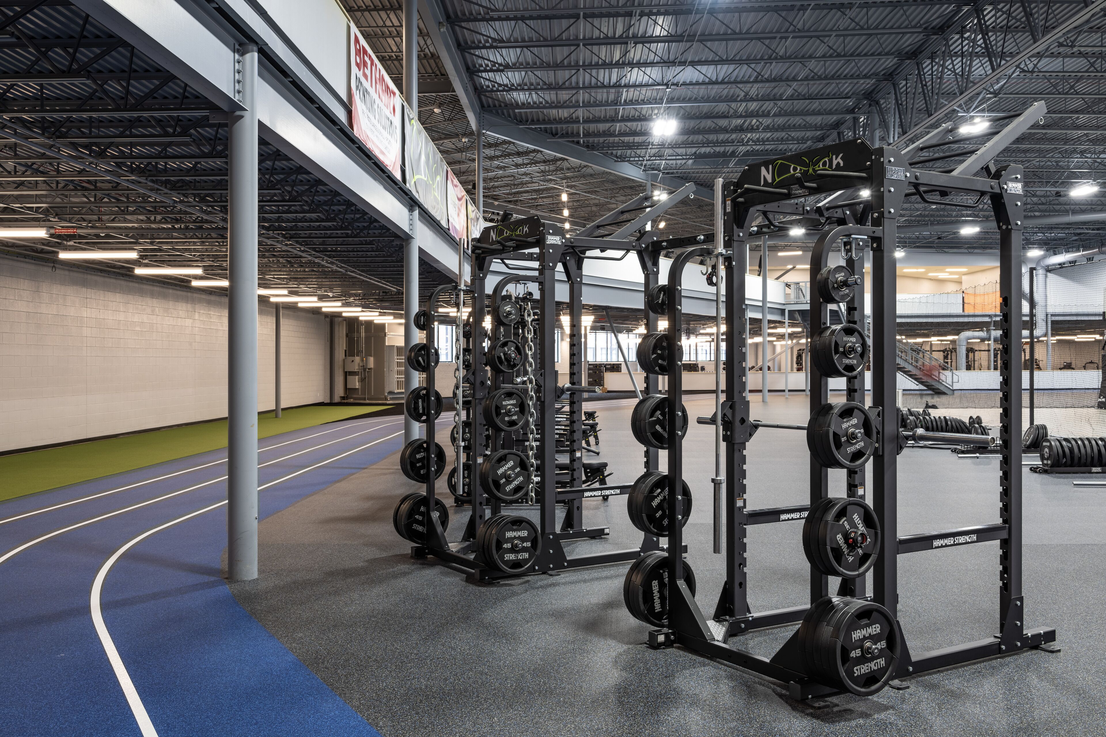 Uma academia com equipamentos de musculação e pista de corrida.