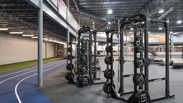 Uma academia com equipamentos de musculação e pista de corrida.