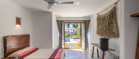 A hotel room with two beds, a ceiling fan, a view of an outdoor pool, and a refrigerator.