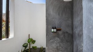 Moderni suihku, jossa on kivilaattalattia, pieni hylly pulloille ja ikkuna vasemmalla puolella.