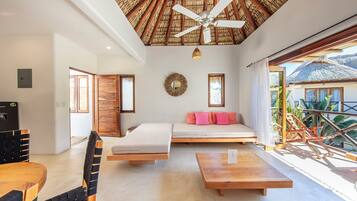Una habitación moderna con ventilador de techo, cama, sofá, mesa de comedor y vistas al exterior.