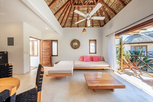 Una habitación moderna con ventilador de techo, cama, sofá, mesa de comedor y vistas al exterior.