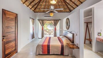 A spacious bedroom with a large bed, a ceiling fan, and a view of the outdoors.