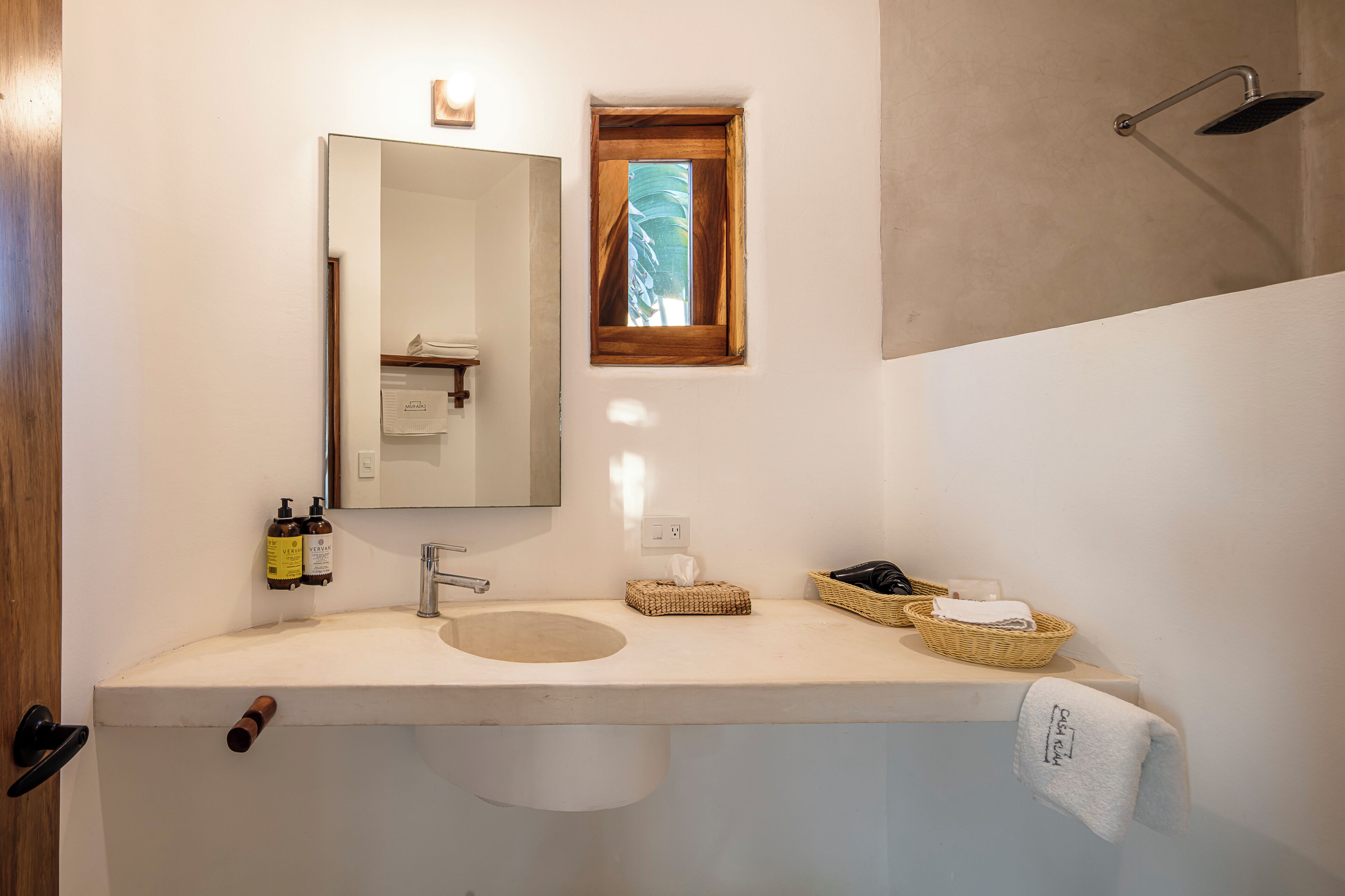 A bathroom with a white sink, a mirror, a small window, and a towel hanging on the wall.