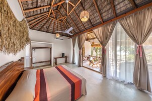 Un dormitorio amplio con una cama grande, techo de madera y vistas al exterior.
