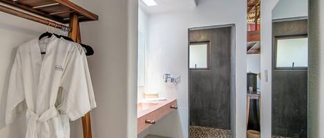 A modern bathroom with a wooden ceiling, a robe rack, a sink, and a mirror.