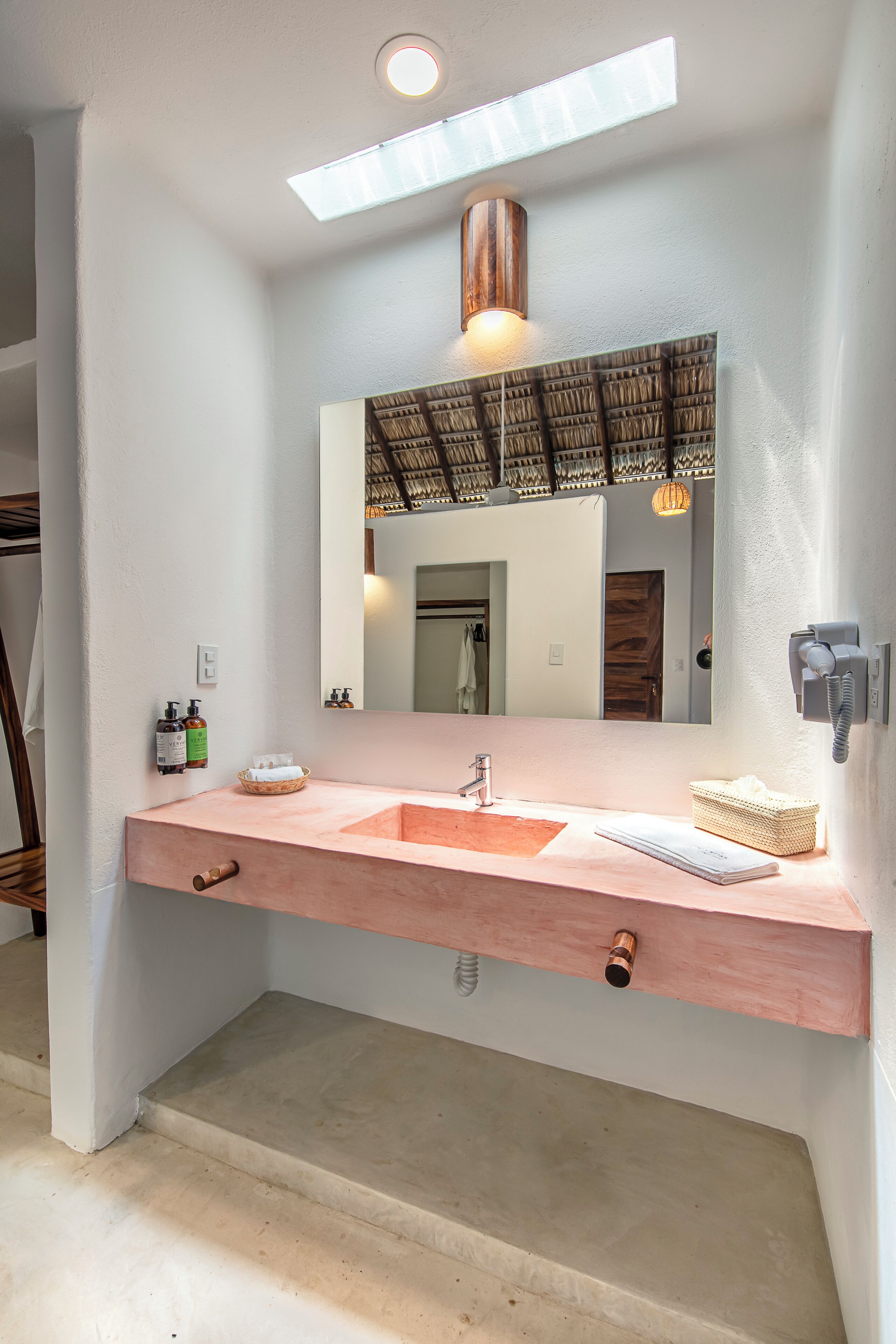 A bathroom with a large mirror, a sink with a wooden countertop, and a towel rack.