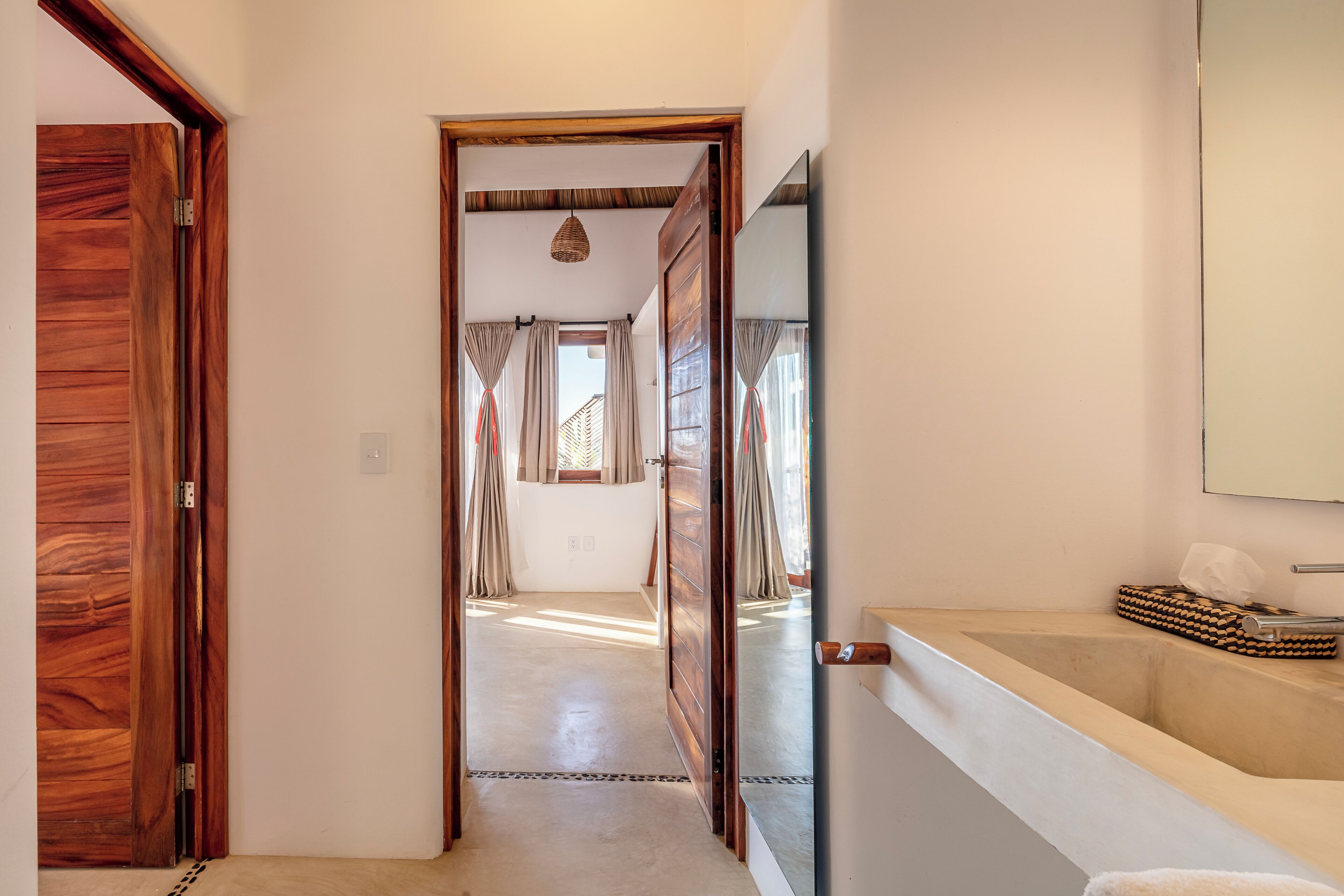 A hallway with wooden doors, a bathroom with a bathtub, and a mirror on the wall.