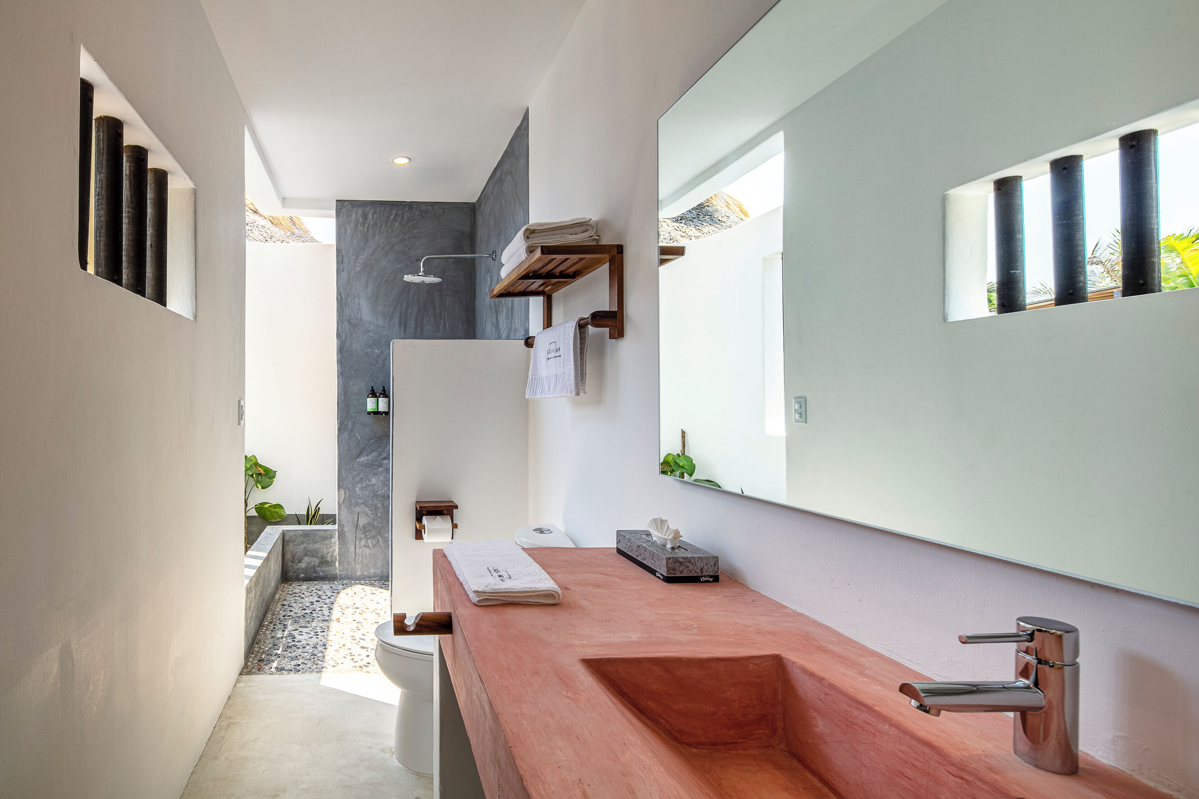 Une salle de bain moderne avec un grand miroir, un meuble-lavabo en bois et un espace douche.
