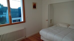 Makuuhuone, jossa on sänky, patteri, ikkuna ja ovi.