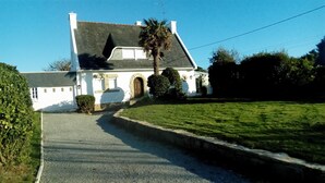 Una casa bianca con tetto grigio, ingresso in pietra e vialetto lastricato che conduce all'ingresso.