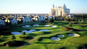A golf course with bunkers, a pathway, and a large building in the background.