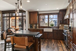 Une cuisine avec des meubles en bois, un grand îlot central et une vue sur l’extérieur.