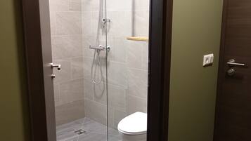 Un baño moderno con ducha acristalada, inodoro blanco y puerta de madera.