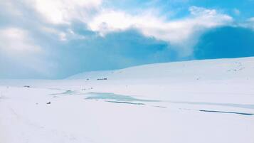 Paisaje nevado con cielo despejado y algunas nubes.