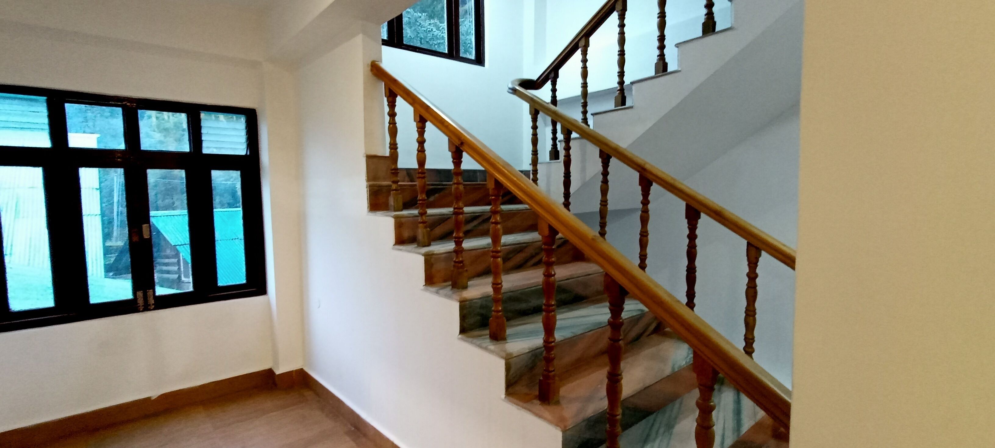 A staircase with wooden balusters and a handrail, leading to an upper floor.