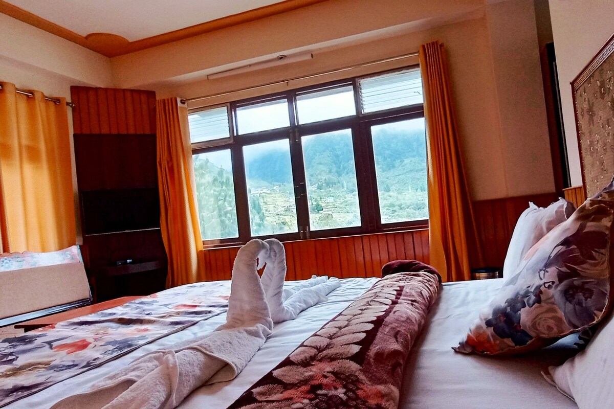 Habitación de hotel con cama, televisión y ventana con cortinas.