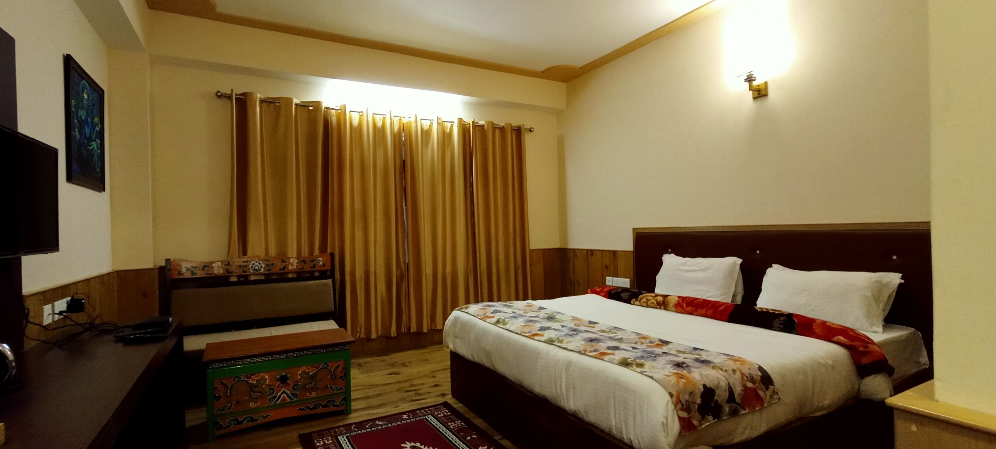 A hotel room with a bed, a desk, a chair, a TV, and curtains.