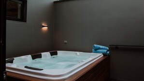Un cuarto de spa con un jacuzzi, bancos de madera y un perchero.