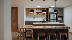 Una cocina moderna con una isla central, sillas de madera e iluminación colgante.