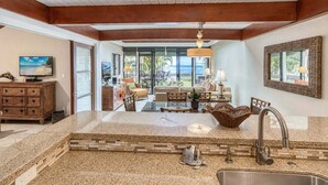 A spacious kitchen with a large island, a dining area with a view, and a living room with a TV.