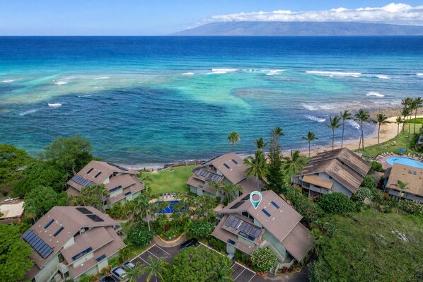 Un quartier résidentiel situé sur la côte, avec des maisons dotées de panneaux solaires, d’une piscine et offrant une vue sur l’océan.