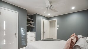 Un dormitorio con cama, ventilador de techo y armario blanco.