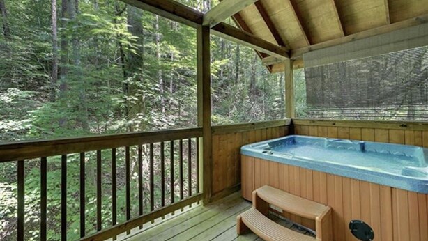 A wooden deck with a hot tub and seating area, surrounded by a forested landscape. - Creekside Paradise Found! One-Bedroom Mountain Cabin in Pigeon Forge (Sevierville)