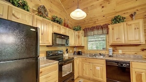 A kitchen with wooden cabinets, a refrigerator, stove, microwave, and dishwasher. - Creekside Paradise Found! One-Bedroom Mountain Cabin in Pigeon Forge (Sevierville)