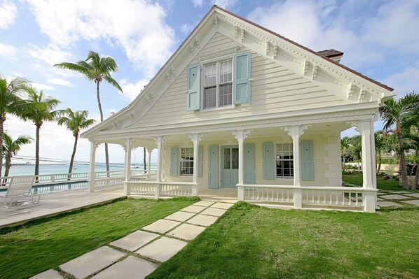 A white colonial-style house with a covered porch, a pool, and palm trees. - Harbourside house with private pool - amazing sea views! (Governor's Harbour)