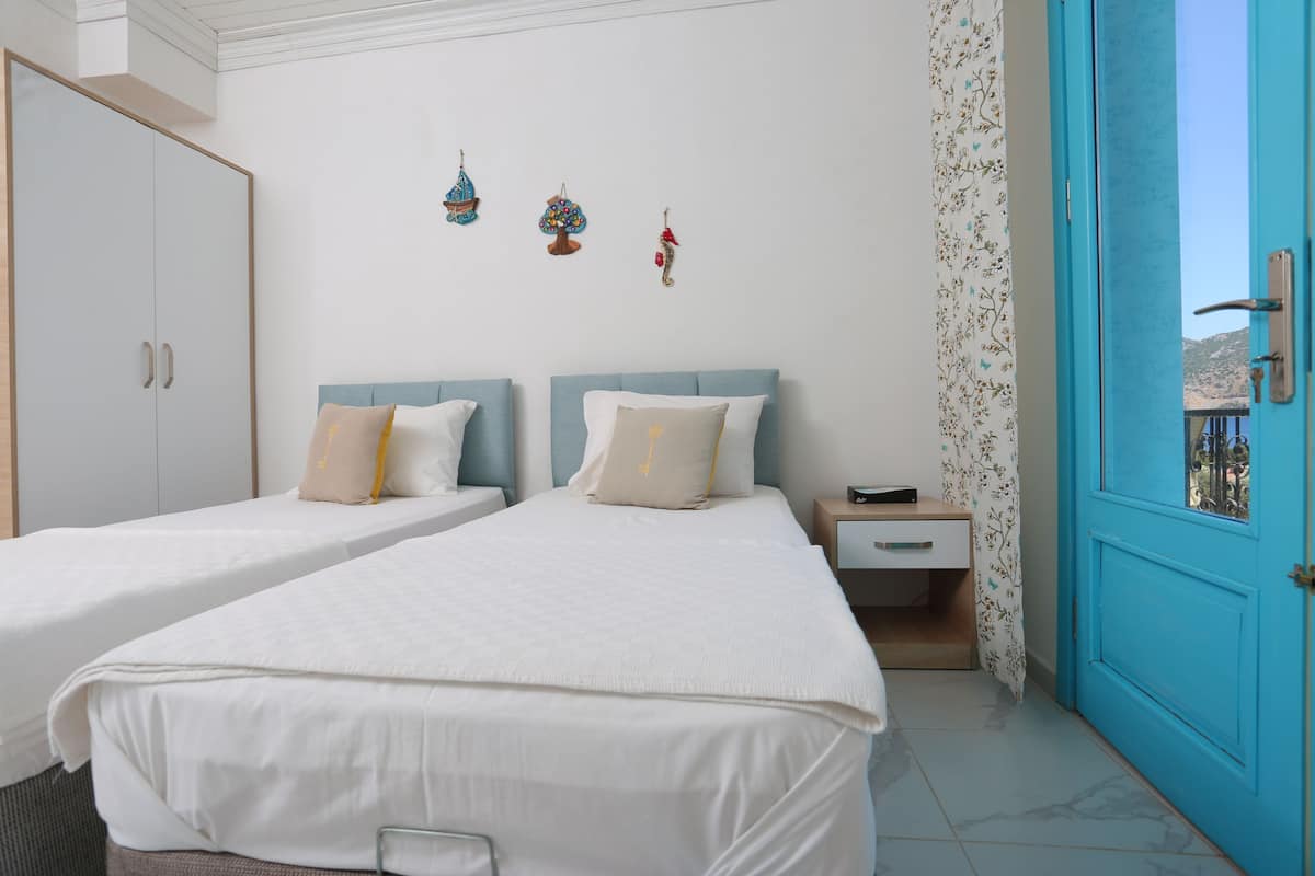 Une chambre avec deux lits, une armoire, une table de chevet et une porte bleue.
