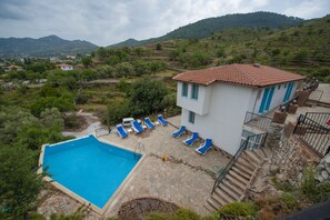 A villa with a swimming pool, blue lounge chairs, and a view of the surrounding hills. - Mavi Melek Hotel (Marmaris)