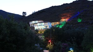 A two-story building with multiple balconies, surrounded by dense vegetation and a hilly landscape. - Mavi Melek Hotel (Marmaris)