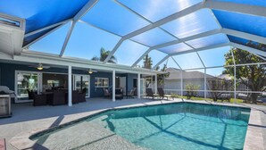 Una piscina cubierta al aire libre con zona de patio, que incluye mobiliario y una parrilla.