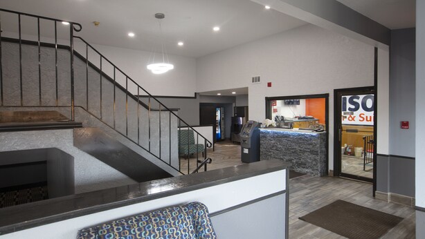A reception area with a staircase, a reception desk, and a sign for 'ISO F & S'. - Bison Inn and Suites (Fargo)