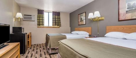 A hotel room with two beds, a desk, a television, and a window with curtains.