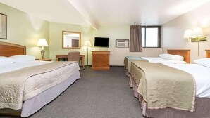 A hotel room with two beds, a desk, a chair, a television, and a window with curtains. - Bison Inn and Suites (Fargo)