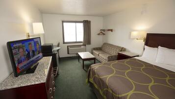 A hotel room with a bed, a television, a sofa, a desk, and a window with curtains.