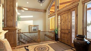 A spacious foyer with a wooden staircase, a large vase, and a framed picture on the wall.