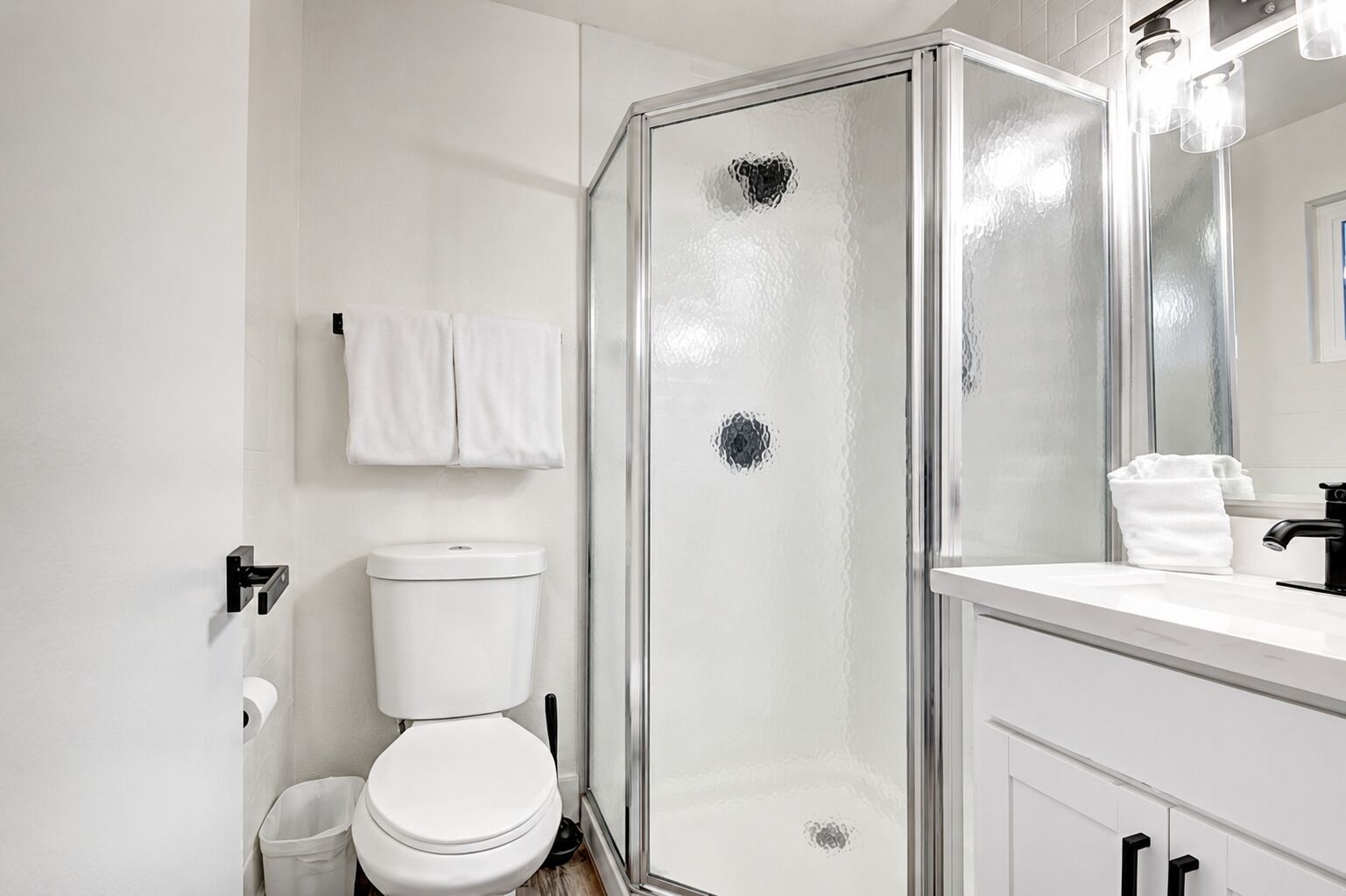 Un baño moderno con cabina de ducha de vidrio, inodoro y lavabo con espejo.