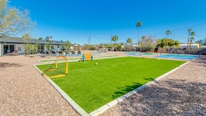 A well-maintained outdoor sports area with a soccer goal, a volleyball net, and a pool table.