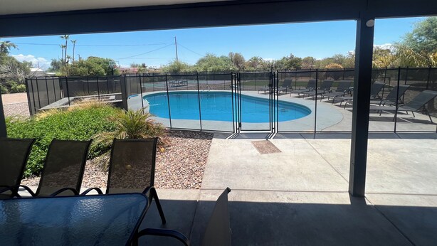 A pool area with a view of the pool, a covered patio, and outdoor seating.