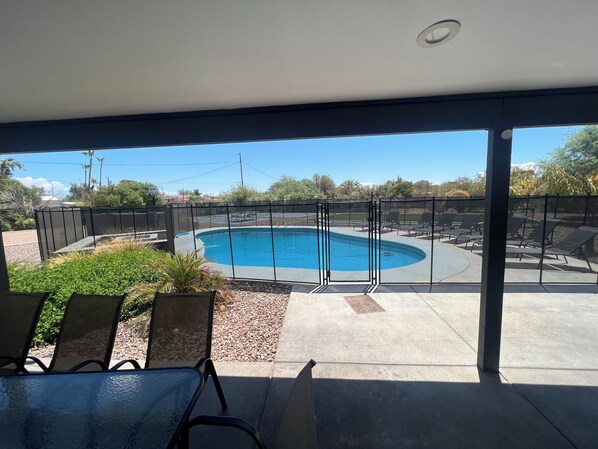 A pool area with a view of the pool, a covered patio, and outdoor seating.
