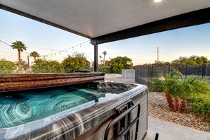 A hot tub with a wooden deck, surrounded by a landscaped garden with palm trees and a basketball hoop. - Scottsdalestays The Amazing 6BR-3BA on Acre-Resort Pool-Grass and Sport Courts (Scottsdale)